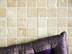 Gros plan sur la mosaïque en travertin beige avec coussin violet