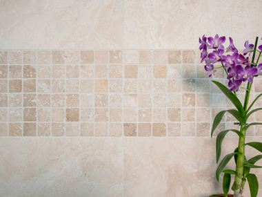 Une orchidée devant le mur en mosaïque en travertin clair