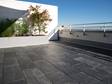 Terrasse avec sol en ardoise noire et mur blanc en arrière-plan