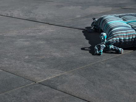 Un coussin posé sur des dalles en grès cérame effet ardoise Alpine Black