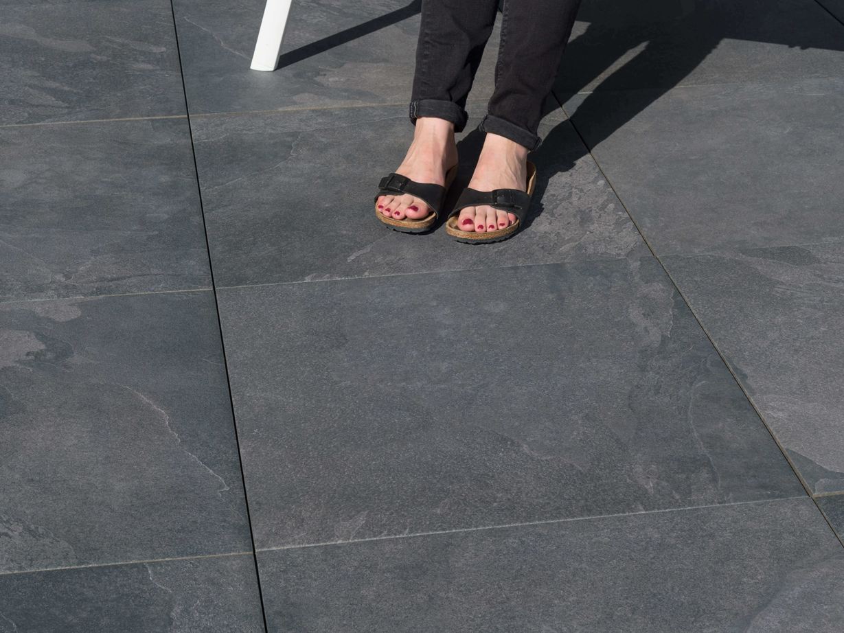 La surface du dallage Alpine Black est antidérapante ! Pieds sur terrasse en dallage effet ardoise Alpine Black