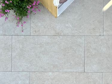 Les dalles imitation travertin Siena vues de haut avec fleurs roses