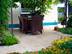 Terrasse couverte avec mobilier en bois tressé, sol en travertin Medium Select et beaucoup de plantes