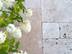 Dalles en travertin beige en format opus romain et fleurs blanches vues de haut