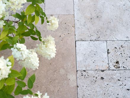 Dalles en travertin beige en format opus romain et fleurs blanches vues de haut