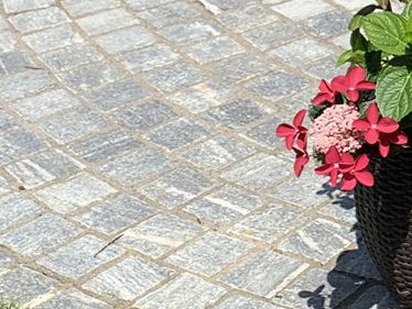 Galerie 1 : pavés en gneiss « Urban Grey Line » dans un décor verdoyant agrémenté de fleurs