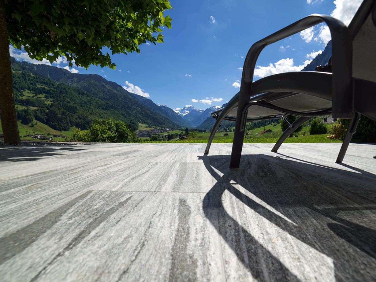 Les veinures des dalles Urban Grey Line sont uniques Terrasse avec dalles de granit Urban Grey Line et chaise longue avec vue sur les Alpes