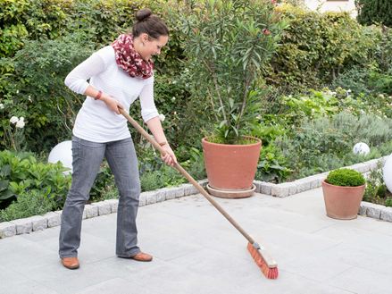 Une femme nettoie une terrasse en granit