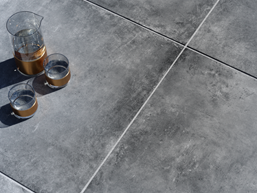 Des dalles imitation béton foncées avec carafe et verres