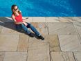 Femme assise au bord de la piscine sur les dalles en grès Yellow Mint