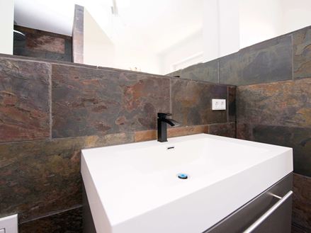 Les carreaux en ardoise Peacock posés au mur derrière un lavabo