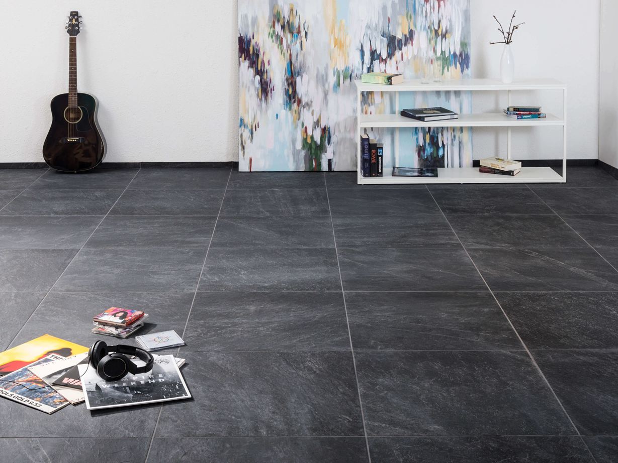Carreaux modernes en grès cérame porcelainé d'aspect ardoise dans un salon avec une peinture moderne à l'arrière-plan et une guitare au mur.
