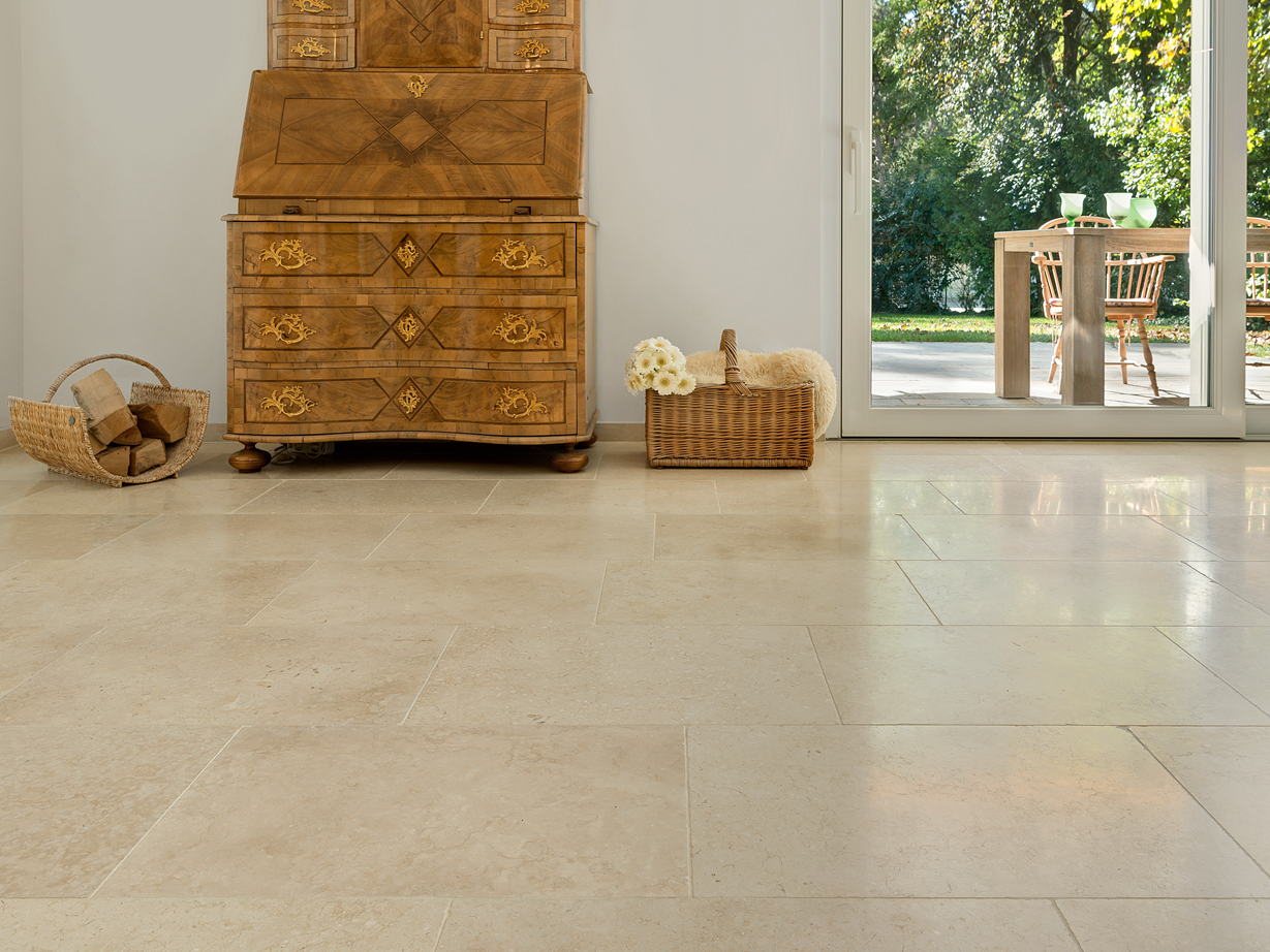 Une teinte beige harmonieuse : le carrelage Cleopatra Light Armoire ancienne en bois sur carrelage clair en pierre calcaire Cleopatra Light, et vue sur la terrasse et le jardin