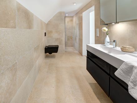 Salle de bains avec meubles modernes et carreaux en pierre calcaire Cleopatra Light au sol et au mur