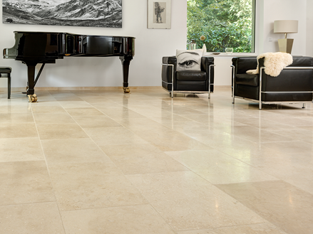 Salon lumineux avec sol en pierre calcaire beige, fauteuils modernes et piano à queue