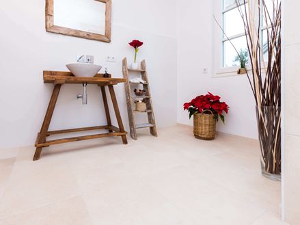 Salle de bains avec meubles en bois et carrelage en pierre naturelle claire en pierre calcaire comme revêtement de sol