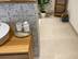 Salle de bains avec éléments en bois et plante décorative, carrelage imitation pierre calcaire Sevilla Cream comme revêtement de sol