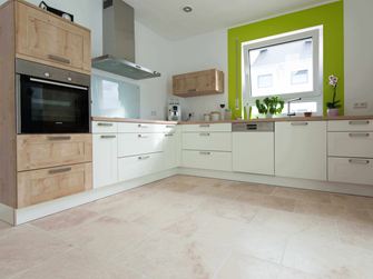 Cuisine blanche avec éléments en bois et cadre de fenêtre vert sur carrelage en travertin Light tambouriné