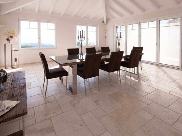 Salle à manger avec haut plafond, table et chaises sur travertin Light en assemblage romain