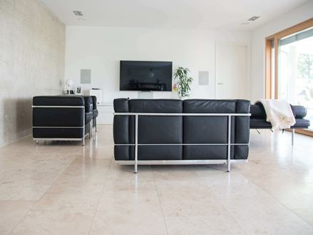 Wohnzimmer mit Travertin Classic Light Fliesen und moderner schwarzer Couch