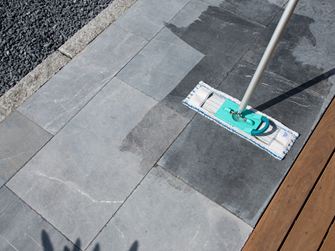 Balai à franges sur une terrasse en pierre calcaire