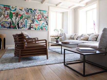 Salon avec canapé confortable, plancher en bois et peinture moderne au mur.