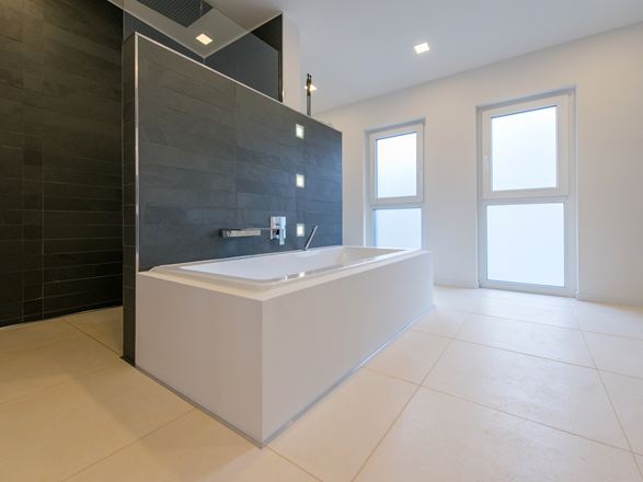 La baignoire avec le revêtement mural en ardoise en arrière et un sol en pierre calcaire brossée