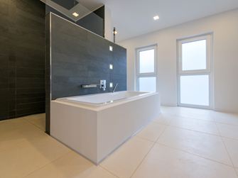 La baignoire avec le revêtement mural en ardoise en arrière et un sol en pierre calcaire brossée