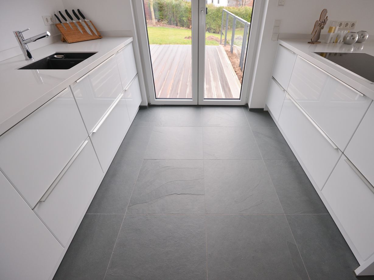 Une cuisine blanche avec des éléments en métal sur un sol en ardoise Grey Slate affinée
