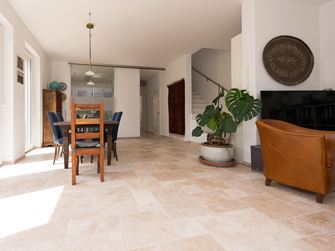 Salon et salle à manger inondés de lumière avec meubles en bois et carreaux de travertin
