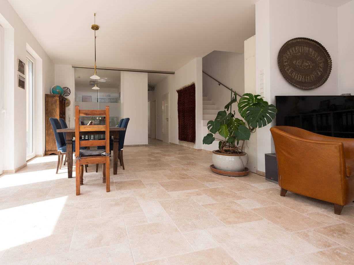 Salon et salle à manger inondés de lumière avec meubles en bois et carreaux de travertin