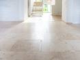 Une surface satinée qu’on a envie de toucher ! Grand espace avec des carreaux de travertin clair Classic Light, à l'arrière-plan un escalier en bois.