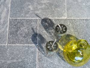 Envie d'été ? Optez pour les dalles Afyon Grey. Un vase décoratif et deux verres sur dalles de marbre Afyon Grey