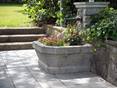 Cette fontaine fleurie met les dalles en valeur. Une ancienne fontaine revisitée en pot de fleur sur la terrasse Kandla Grey en grès