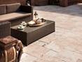 Les cavités du travertin accentuent son côté rustique. Un sofa de jardin avec une table basse où est servi du thé et un éléphant en accessoire sur le travertin Medium