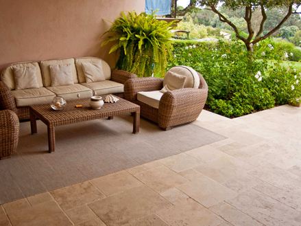 une terasse table basse canapés et verdure sur la droite sol en travertin