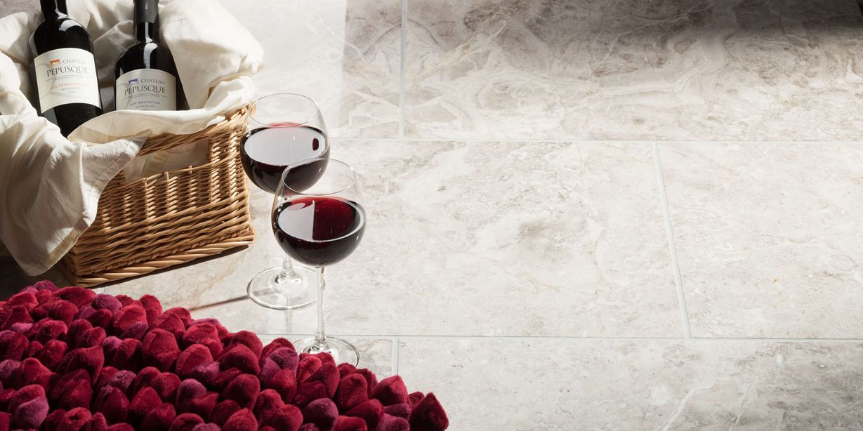 Zwei Weingläser stehen neben gefülltem Erdbeerkorb auf Marmorfliesen Silver Shadow poliert