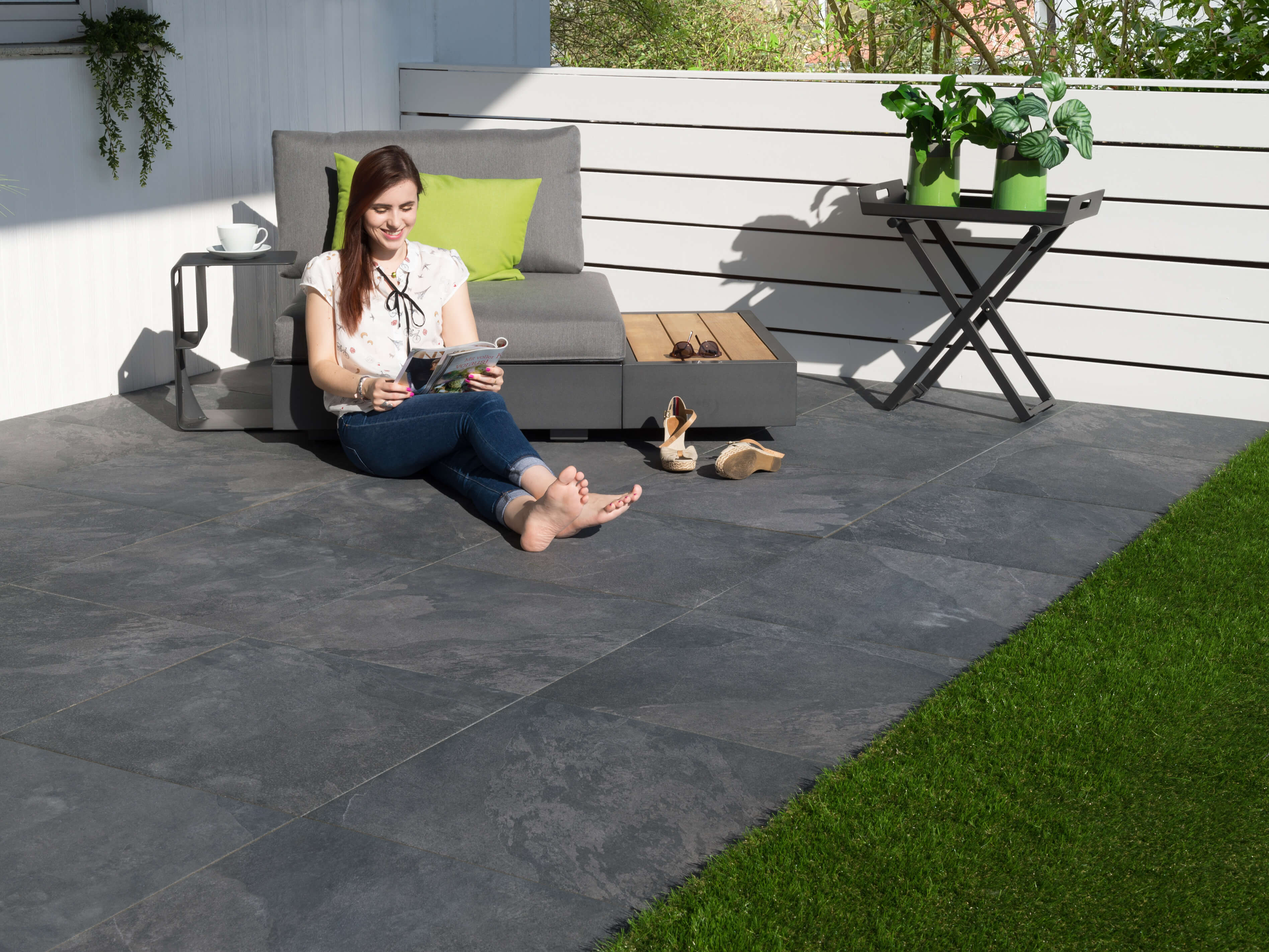 Frau sitzt auf Terrassenplatten Alpine Black