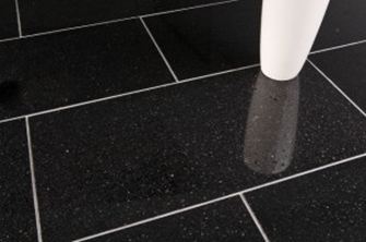 Eine weiße Vase auf schwarzen Granitfliesen mit hellen Fugen