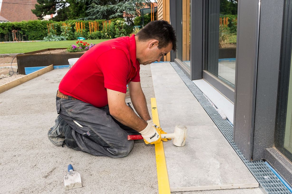 Le carreleur pose des carreaux de grès cérame sur la terrasse