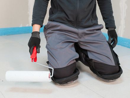 Fliesenleger trägt Grundiermittel auf den Estrich auf