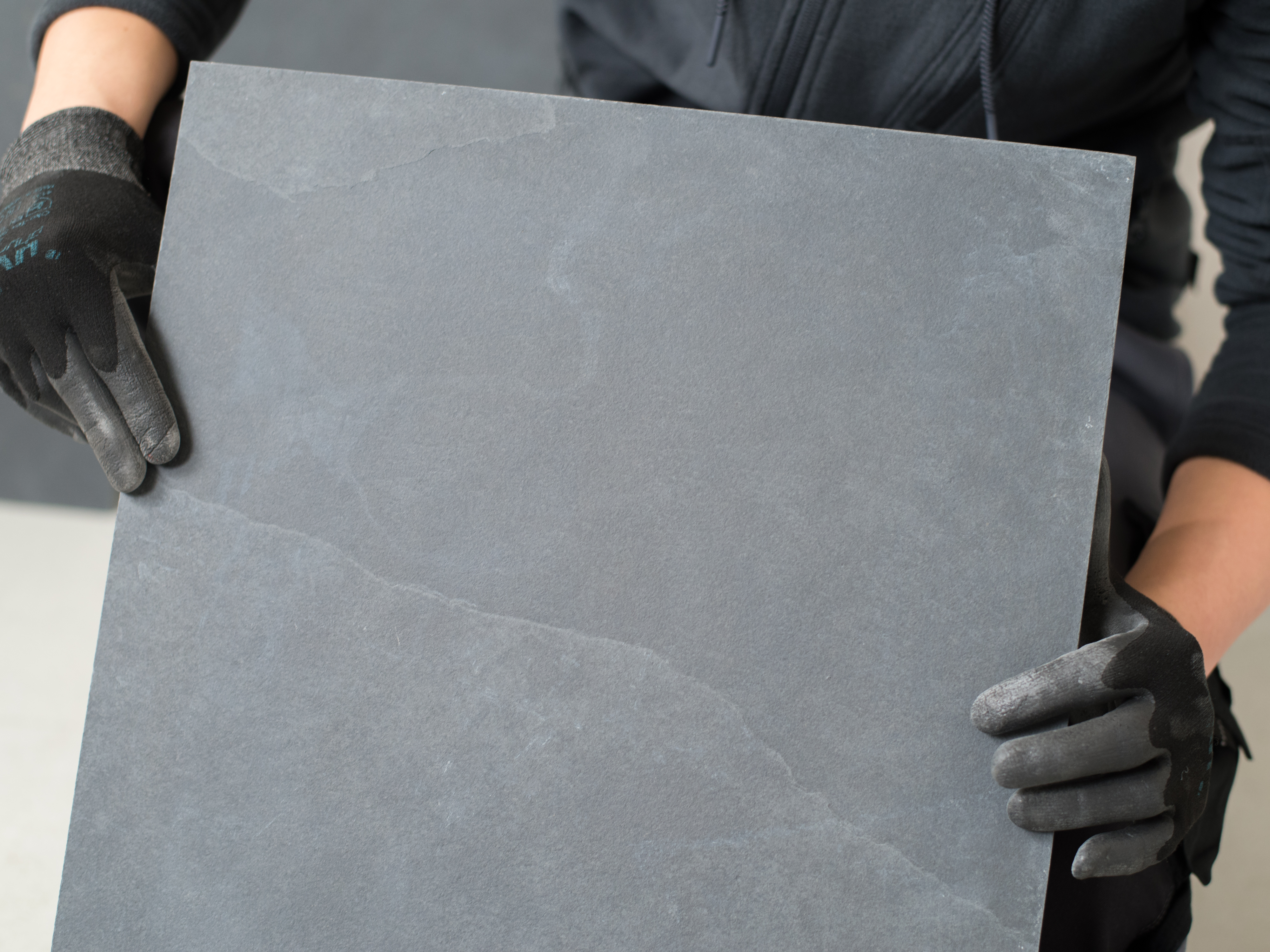 Un carreleur tient un carreau d'ardoise dans la caméra