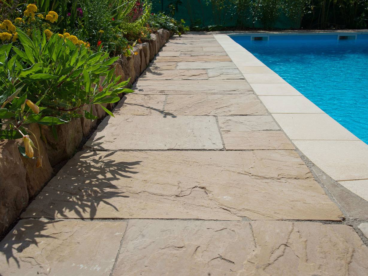 Sentier au bord de la piscine avec des dalles de grès Yellow Mint et un lit de jardin