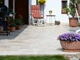Terrasse avec dalles de travertin léger, chaise longue et bac à plantes au premier plan