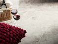 Deux verres à vin se tiennent à côté du panier avec une bouteille de vin et un coussin rouge sur des carreaux de marbre Silver Shadow poli