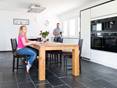 Salle à manger avec table en bois et ameublement moderne, carrelage en ardoise comme revêtement de sol